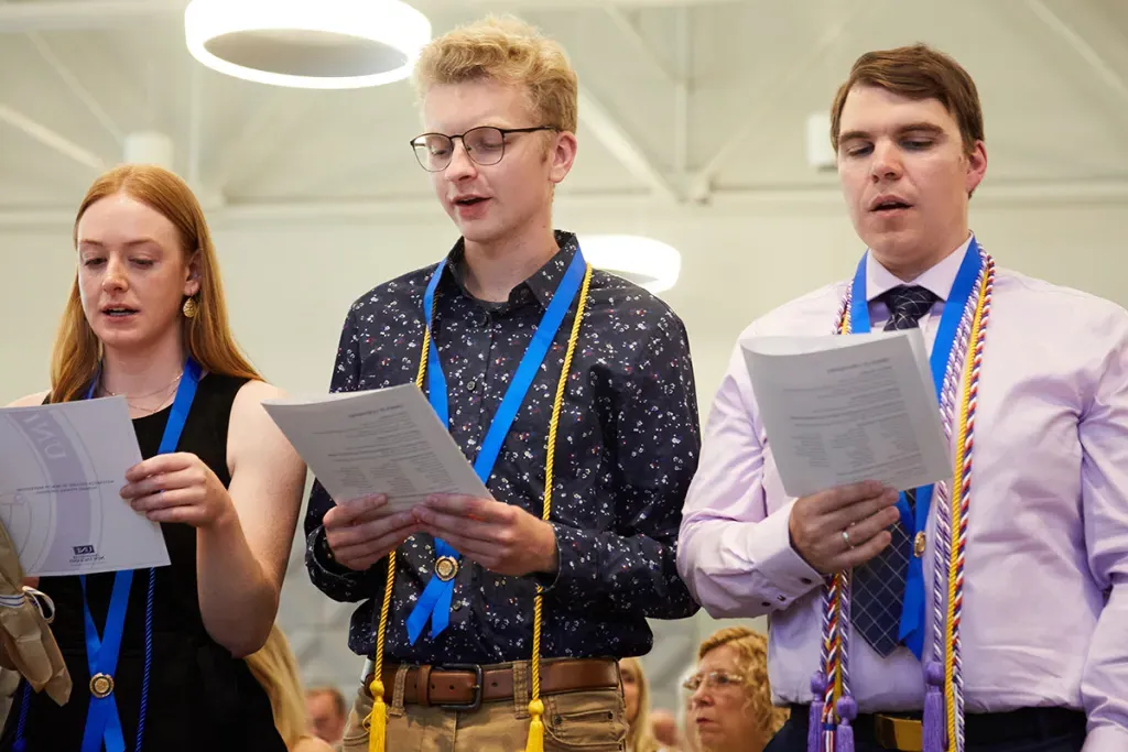 Three students wearing nursing cords hold up and recite the nursing pledge